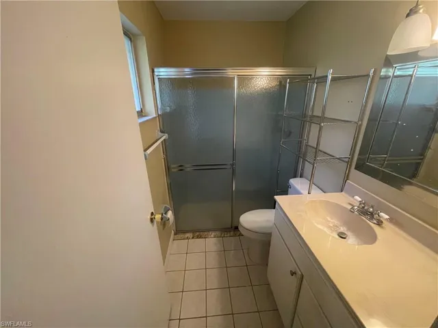 Full bathroom with toilet, vanity, a shower stall, and tile patterned floors
