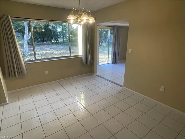 Unfurnished dining area with tile patterned floors, baseboards, and an inviting chandelier