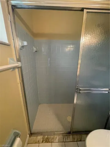 Bathroom with tile patterned floors, toilet, and a shower stall
