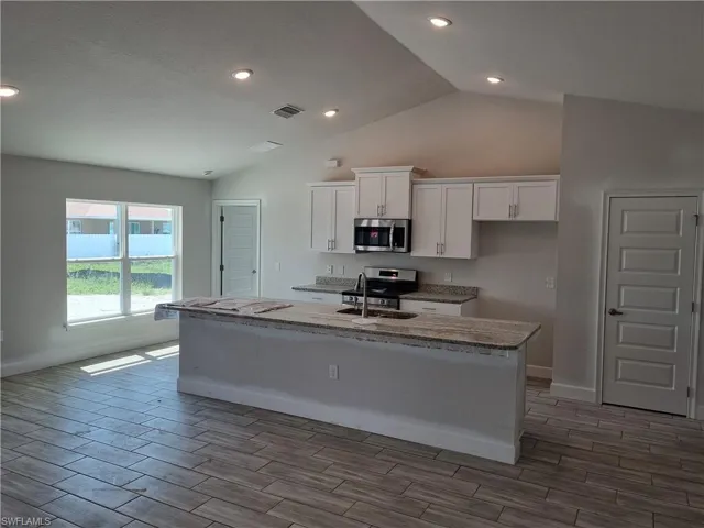 Kitchen featuring white cabinets, an island with sink, stainless steel appliances, and sink