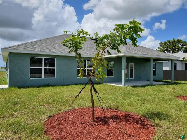 Back of house with a lawn and a patio