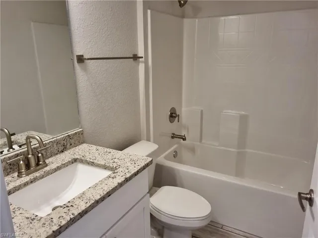 Full bathroom with shower / tub combination, vanity, toilet, and hardwood / wood-style flooring