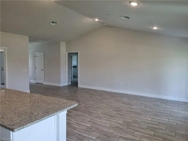 Unfurnished living room featuring vaulted ceiling and light hardwood / wood-style floors