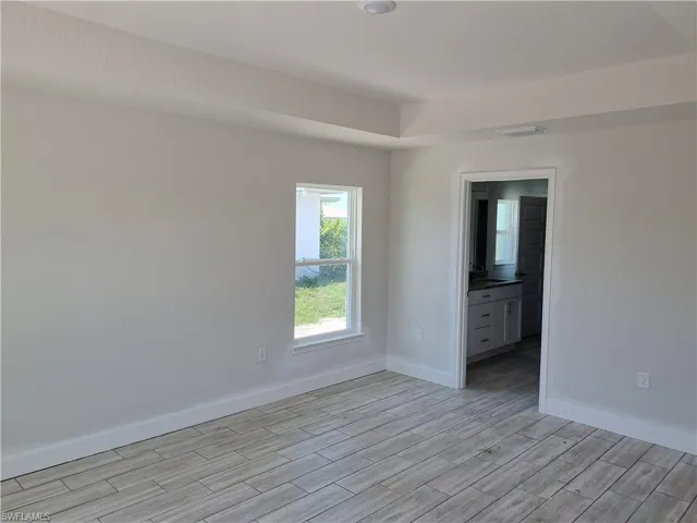 Unfurnished bedroom featuring ensuite bath and light wood-type flooring