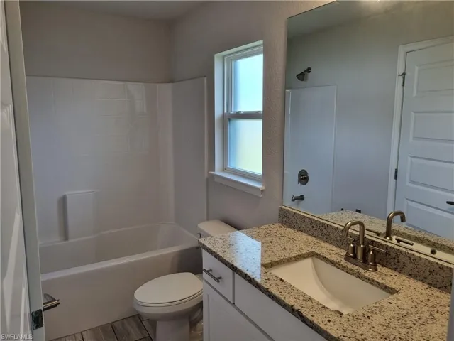 Full bathroom featuring hardwood / wood-style floors, vanity, toilet, and bathtub / shower combination