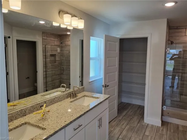 Bathroom featuring dual vanity, toilet, and walk in shower