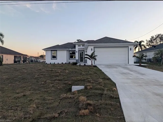 Prairie-style house with driveway, stucco siding, a garage, and a front yard