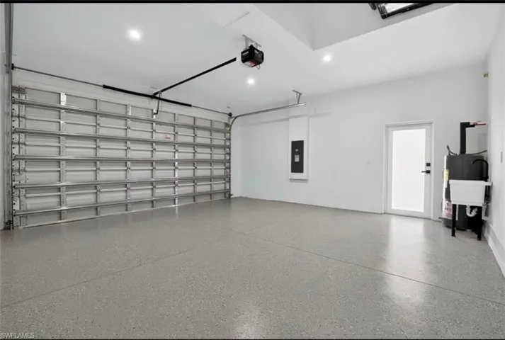 Garage with recessed lighting, electric panel, and a garage door opener
