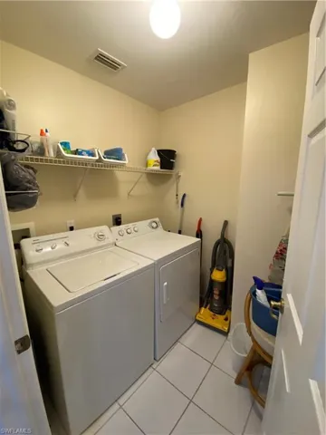 Laundry area with washer and dryer and light tile patterned flooring