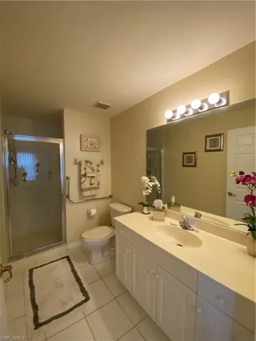 Full bathroom with a shower stall, vanity, and light tile patterned floors