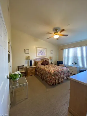 Bedroom featuring light carpet, vaulted ceiling, and a ceiling fan