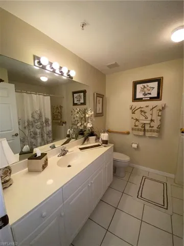 Full bathroom with vanity, curtained shower, and light tile patterned floors