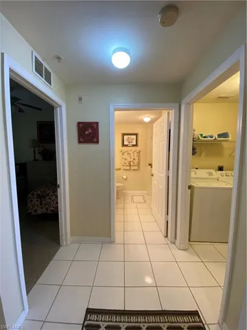 Corridor featuring washing machine and clothes dryer and light tile patterned floors