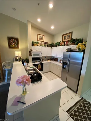 Kitchen featuring a peninsula, white cabinets, refrigerator, white stove, and recessed lighting