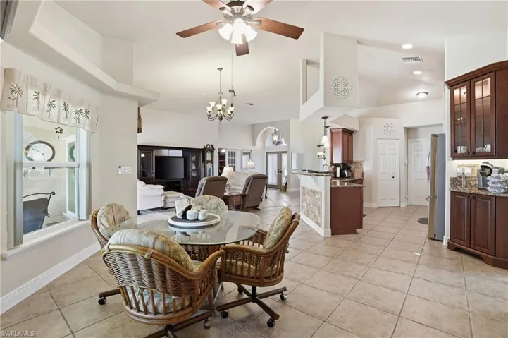 Dining space with light tile patterned floors, high vaulted ceiling, a ceiling fan, a chandelier, and arched walkways