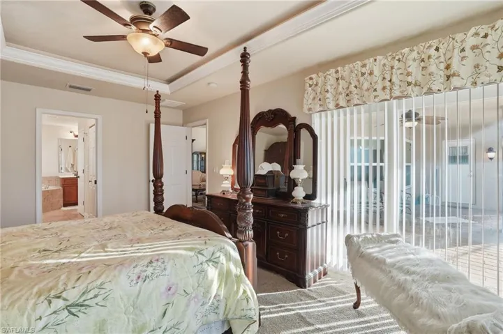 Bedroom with ornamental molding, a raised ceiling, carpet floors, access to exterior, and ceiling fan