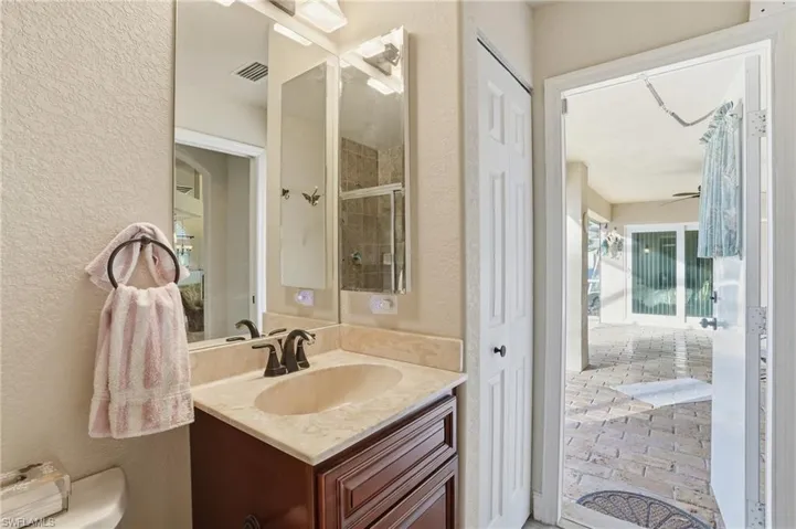 Full bath featuring a textured wall, vanity, and a shower stall