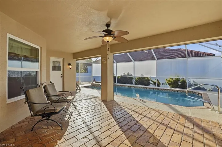 Outdoor pool with glass enclosure, a sunroom, and a patio