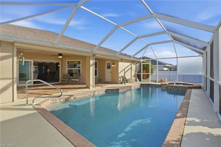 View of pool featuring a sunroom, a lanai, a pool with connected hot tub, and a patio area