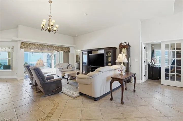 Living room featuring light tile patterned floors, plenty of natural light, high vaulted ceiling, and a chandelier