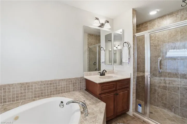 Full bath featuring vanity, a stall shower, and a bath