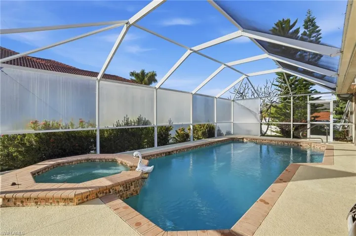 View of pool featuring a lanai, a sunroom, a pool with connected hot tub, and a patio area