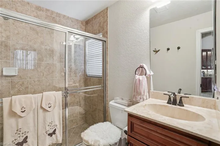 Bathroom with a textured wall, a shower stall, and vanity