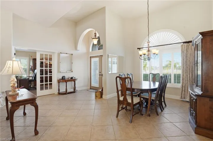 Dining room featuring a towering ceiling, light tile patterned floors, arched walkways, and a chandelier