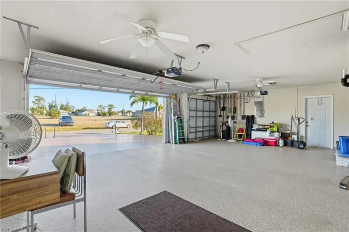 Garage with a ceiling fan, electric panel, and a garage door opener