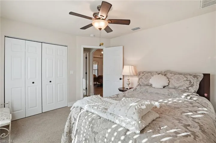 Bedroom featuring a ceiling fan, light carpet, and a closet