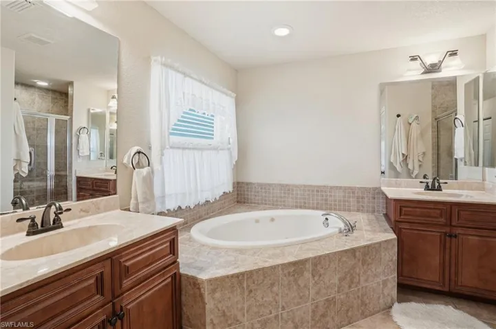 Full bathroom featuring a stall shower, two vanities, and a bath