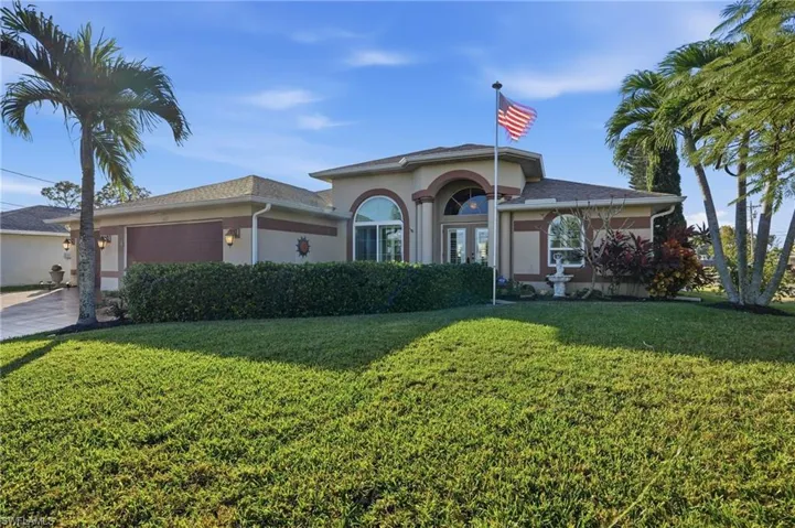 View of front facade featuring an attached garage, stucco siding, and a front lawn
