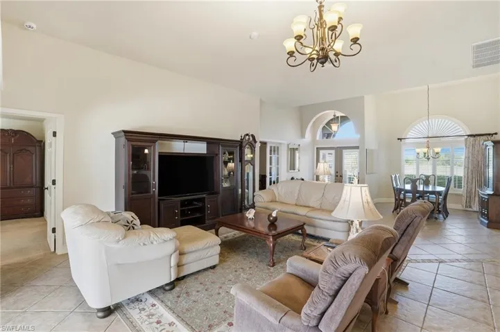 Living room featuring a chandelier, light tile patterned floors, a towering ceiling, and french doors