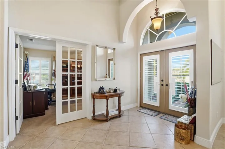 Entrance foyer featuring french doors, light tile patterned floors, and a towering ceiling