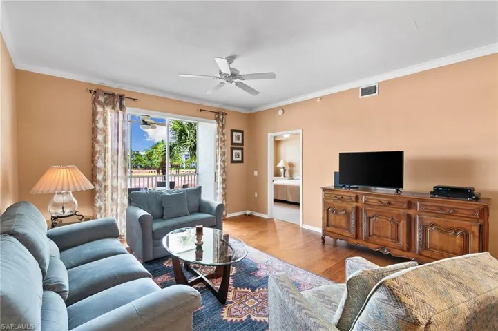 Living room with ceiling fan, hardwood / wood-style floors, and ornamental molding