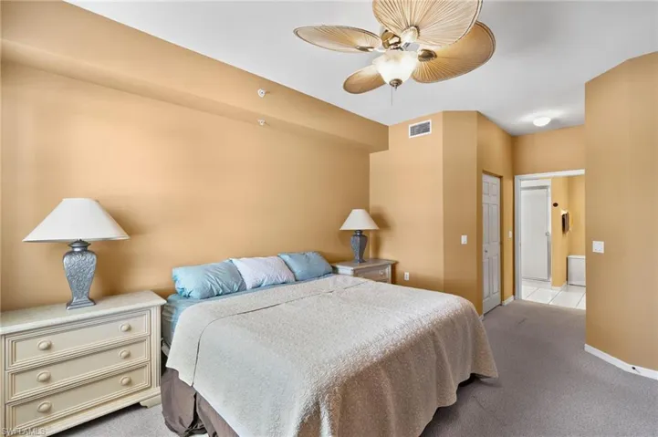 Carpeted bedroom featuring ceiling fan and a closet