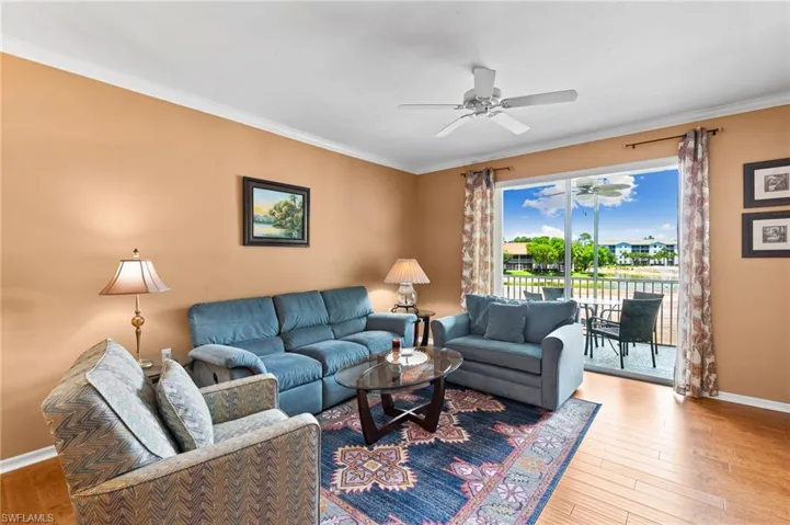 Living room featuring ornamental molding, wood-type flooring, and ceiling fan