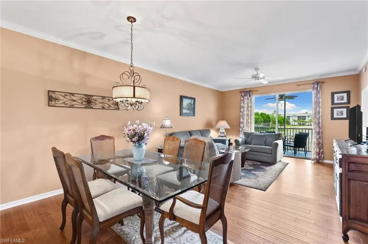 Dining area with crown molding, hardwood / wood-style flooring, and ceiling fan with notable chandelier