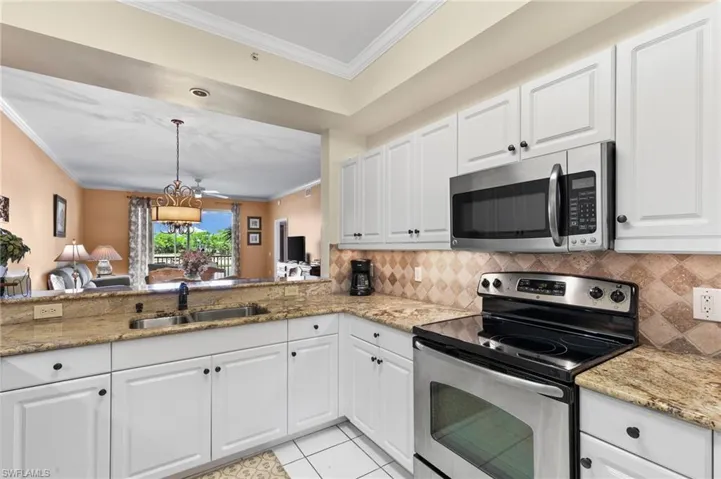 Kitchen featuring crown molding, stainless steel appliances, light tile floors, sink, and white cabinets