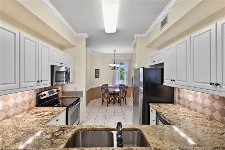 Kitchen with white cabinetry, backsplash, and stainless steel appliances