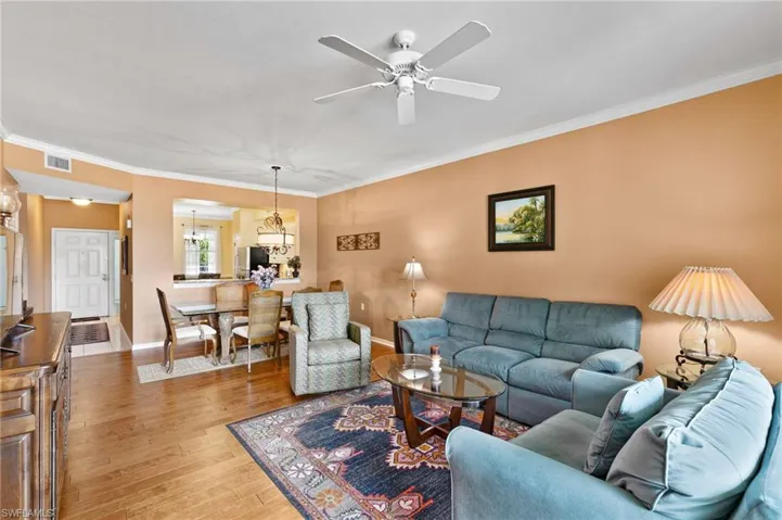 Living room with light hardwood / wood-style floors, crown molding, and ceiling fan
