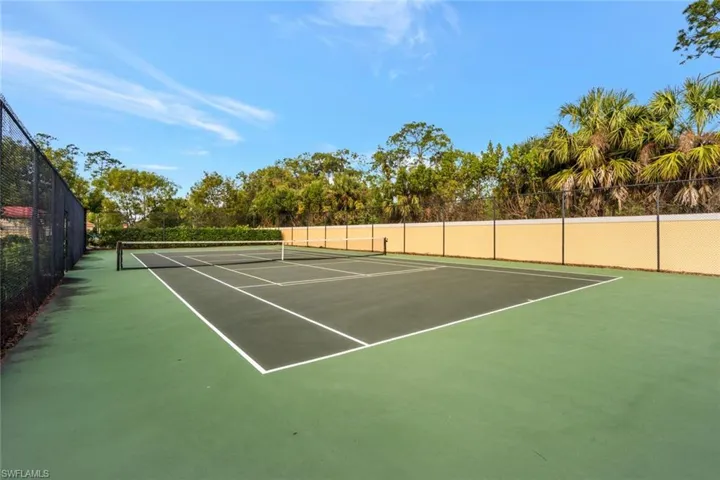 View of tennis court featuring fence and community basketball court