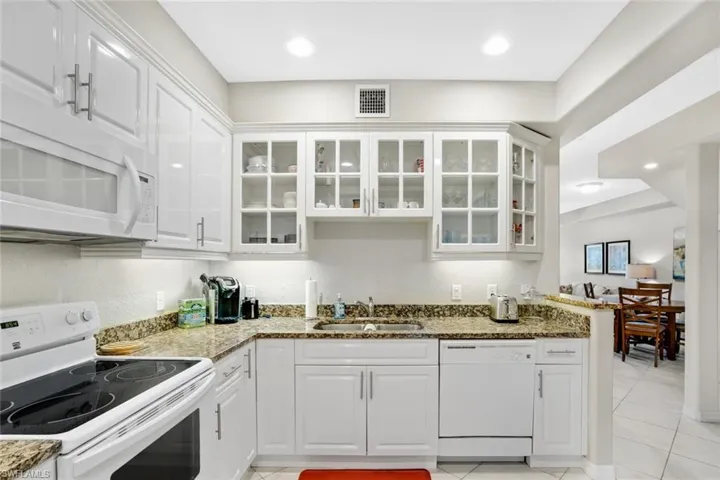 Kitchen featuring white appliances, a sink, white cabinets, and light tile patterned floors