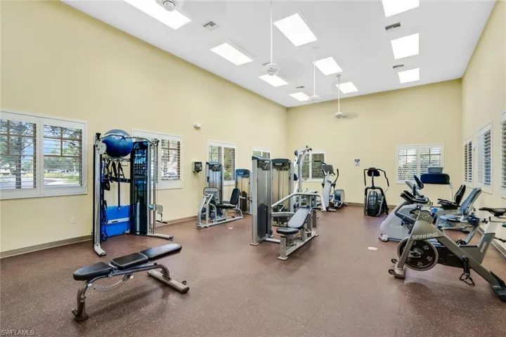 Gym with a towering ceiling, a skylight, and baseboards