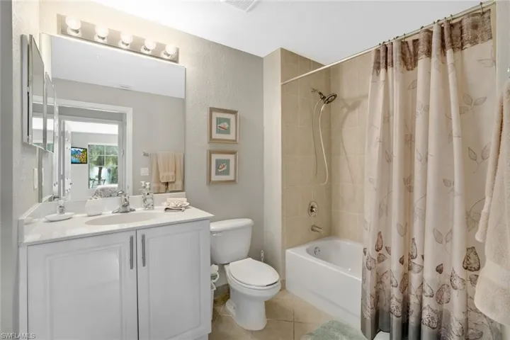 Bathroom featuring toilet, tile patterned flooring, vanity, shower / bath combo, and a textured wall