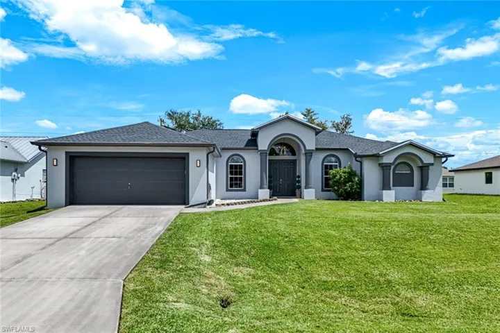 Ranch-style house with stucco siding, driveway, a garage, a front lawn, and a shingled roof