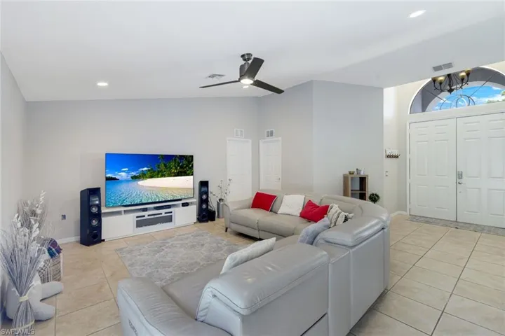 Living room with light tile patterned flooring, recessed lighting, ceiling fan, and a chandelier