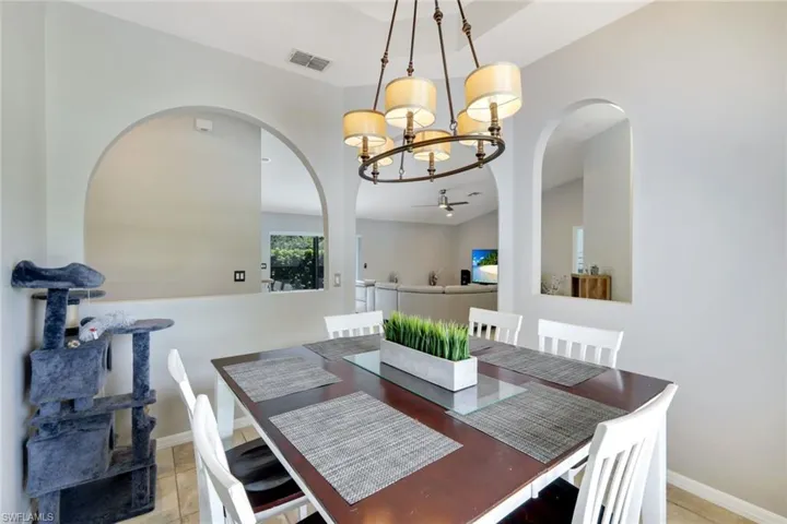 Dining room featuring a chandelier, light tile patterned flooring, and arched walkways