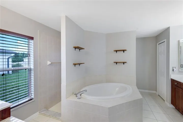 Bathroom with vanity, a bath, light tile patterned floors, and a walk in shower