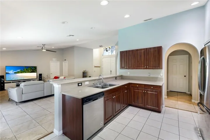 Kitchen with a peninsula, light tile patterned floors, a ceiling fan, appliances with stainless steel finishes, and light countertops